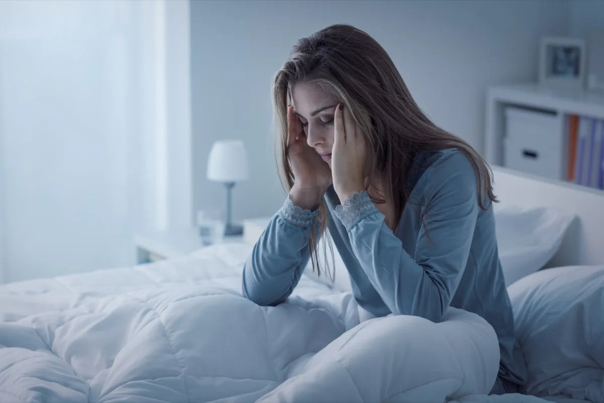 Tired woman sitting awake in bed